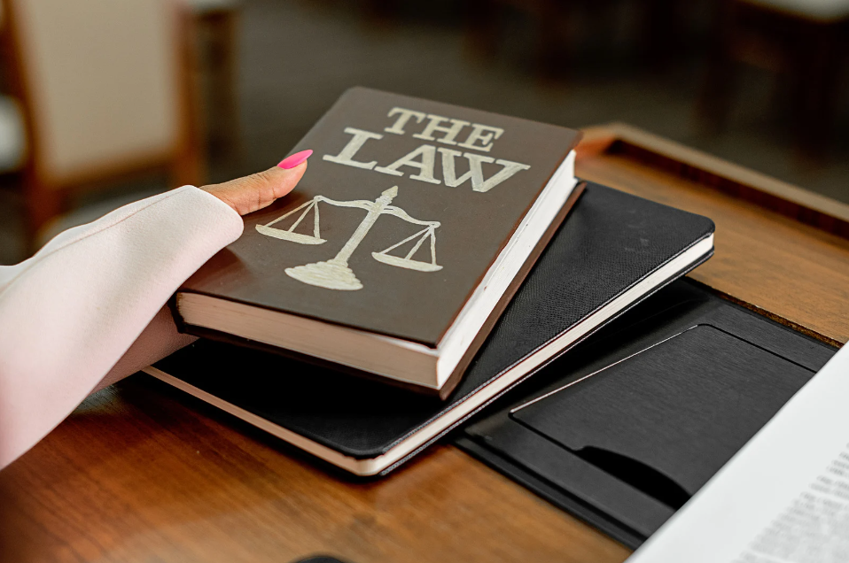 Close-up of a hand holding a law book with scales of justice on the cover, symbolizing the legal framework and regulations in Pakistan's vape industry.