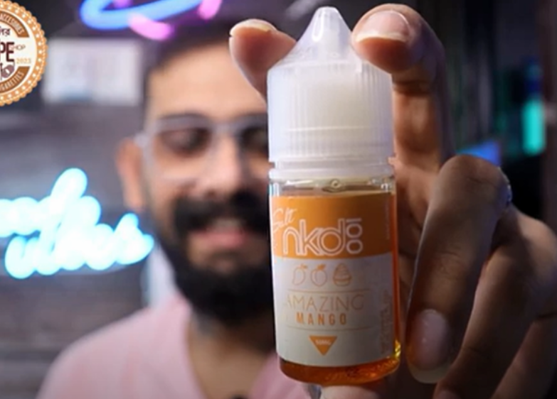 Close-up of a man holding a mango-flavored e-liquid bottle, representing marketing efforts for flavored e-liquids in the U.S. industry.
