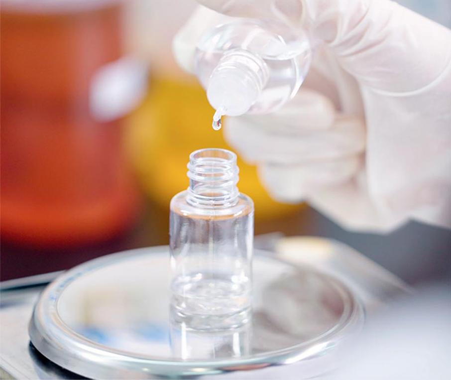 e-liquid-bulk-filling-process A gloved hand carefully pouring e-liquid into a small bottle on a precision scale, illustrating the bulk filling process for high-quality e-liquid production.